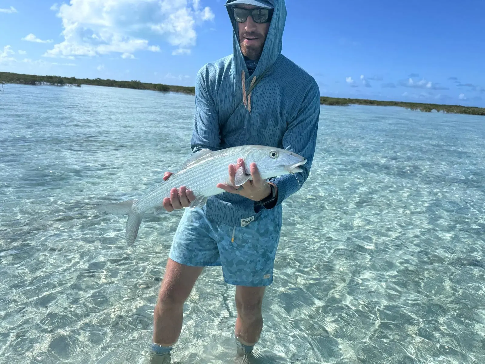 Angler holding a bonefish on the clear flats of Great Exuma