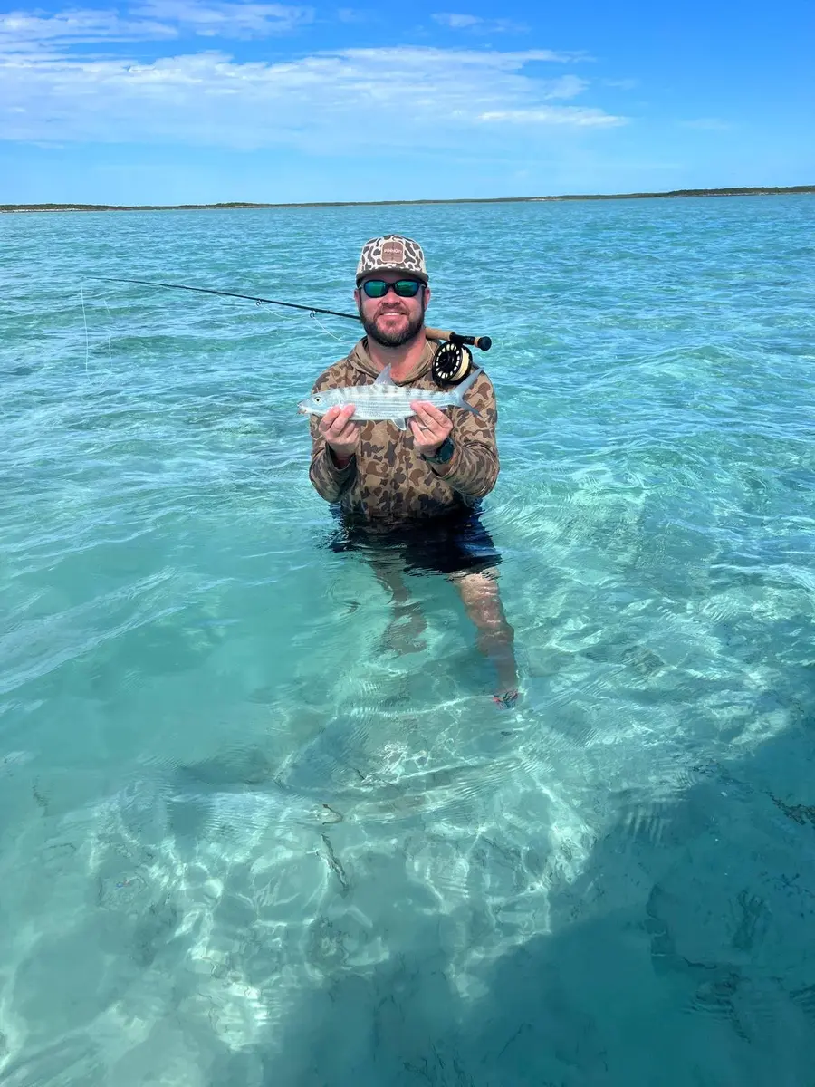 Guest holding a bonefish while wading in Great Exuma