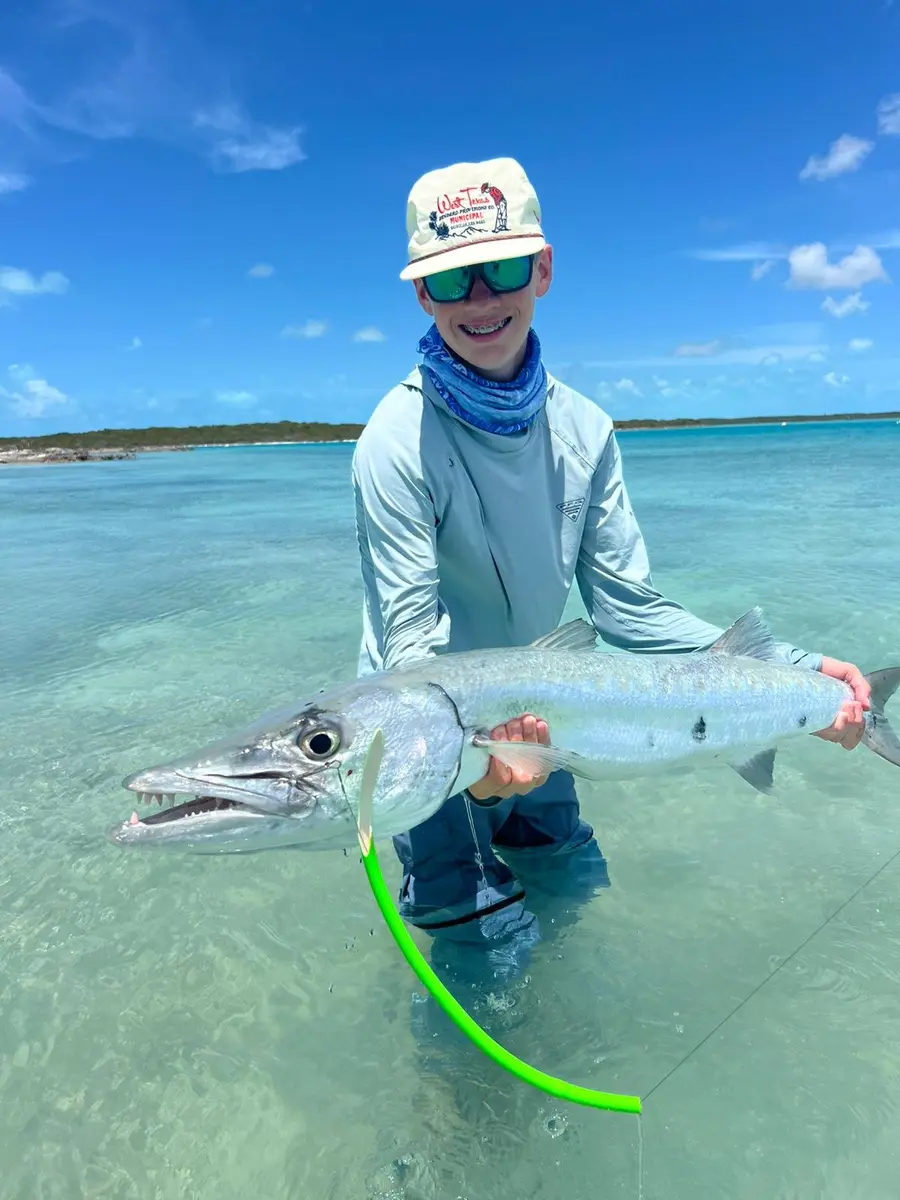 Guest holding a barracuda caught in shallow Exuma water