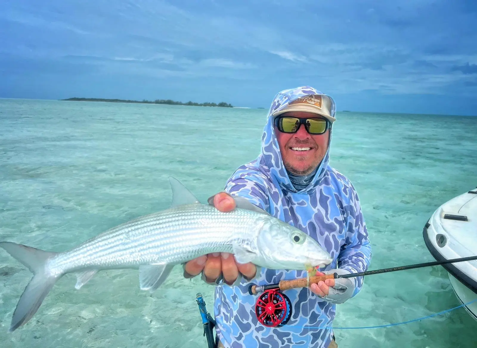 Angler presenting a bonefish beside an Exuma skiff